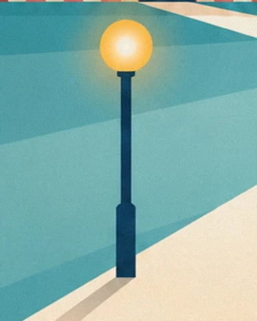 Un lampadaire bleu sombre au globe jaune lumineux, au bord d’une allée crème